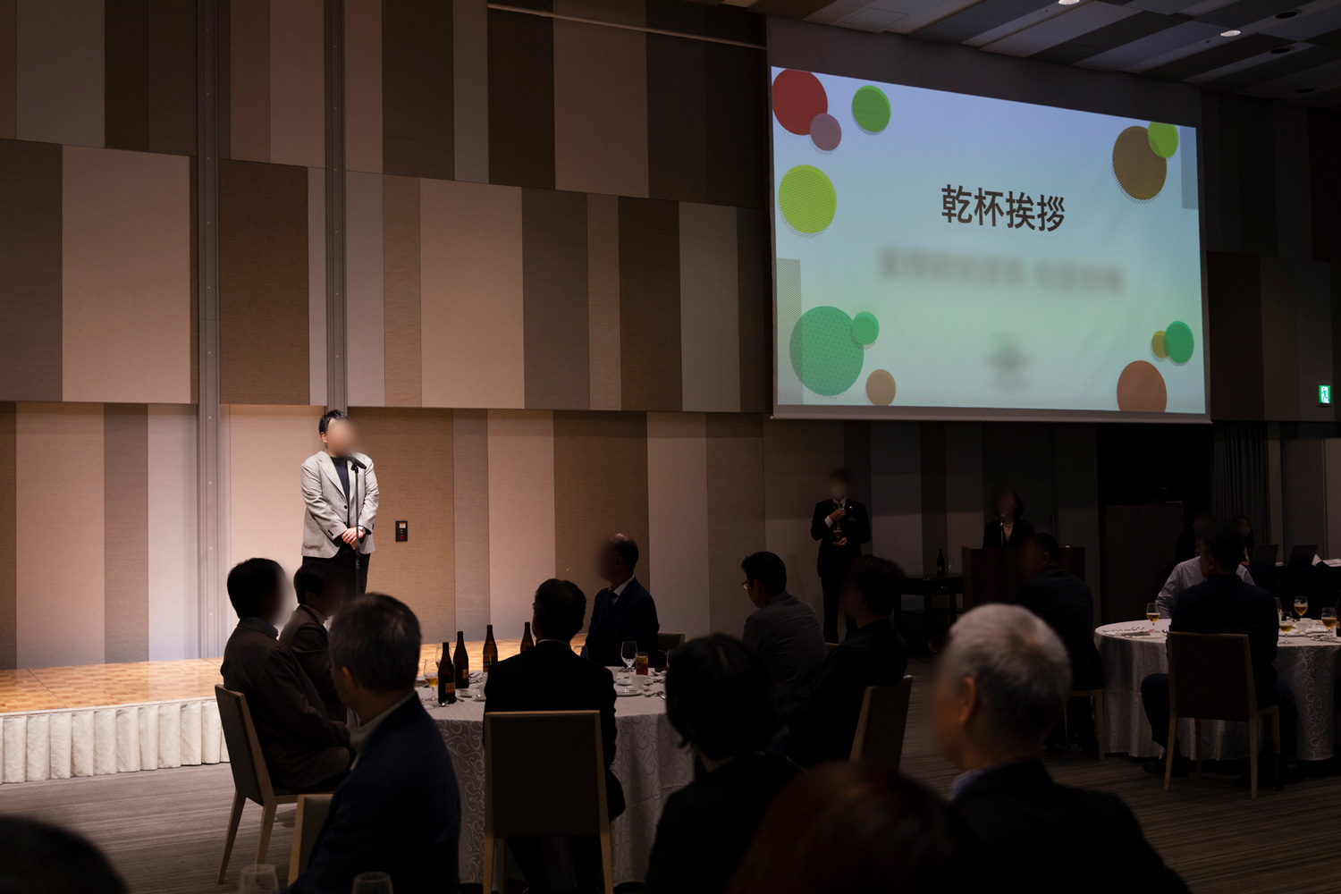 暗転した会場のステージに登壇し、プレゼンを行う男性