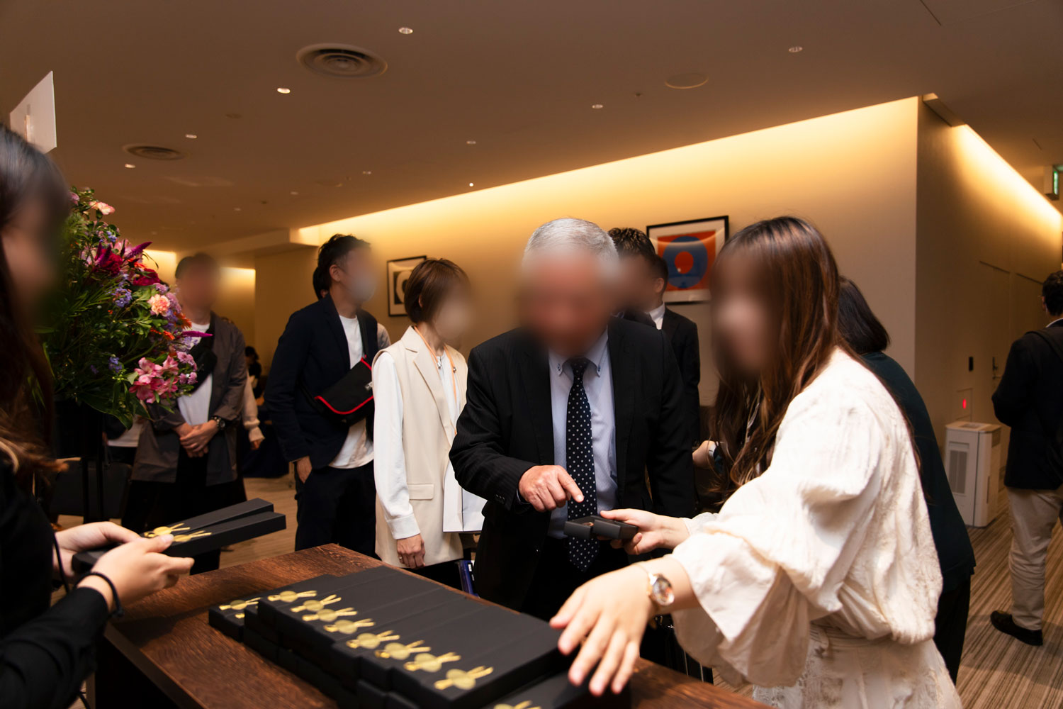 会場で受付をする白髪の男性と、受付を促す女性