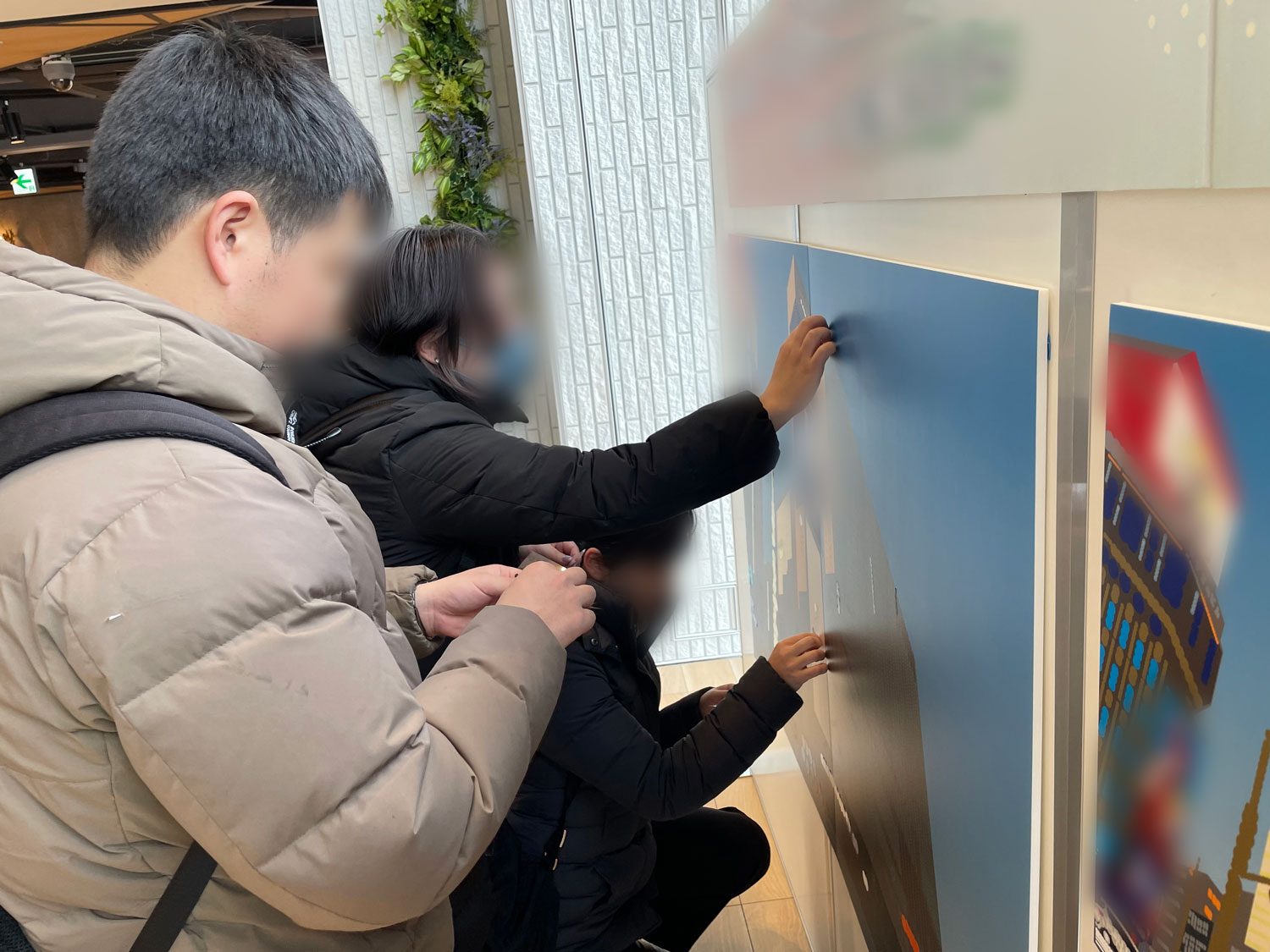 商業施設の一角に設けられたシールアートイベントに参加する家族の後ろ姿